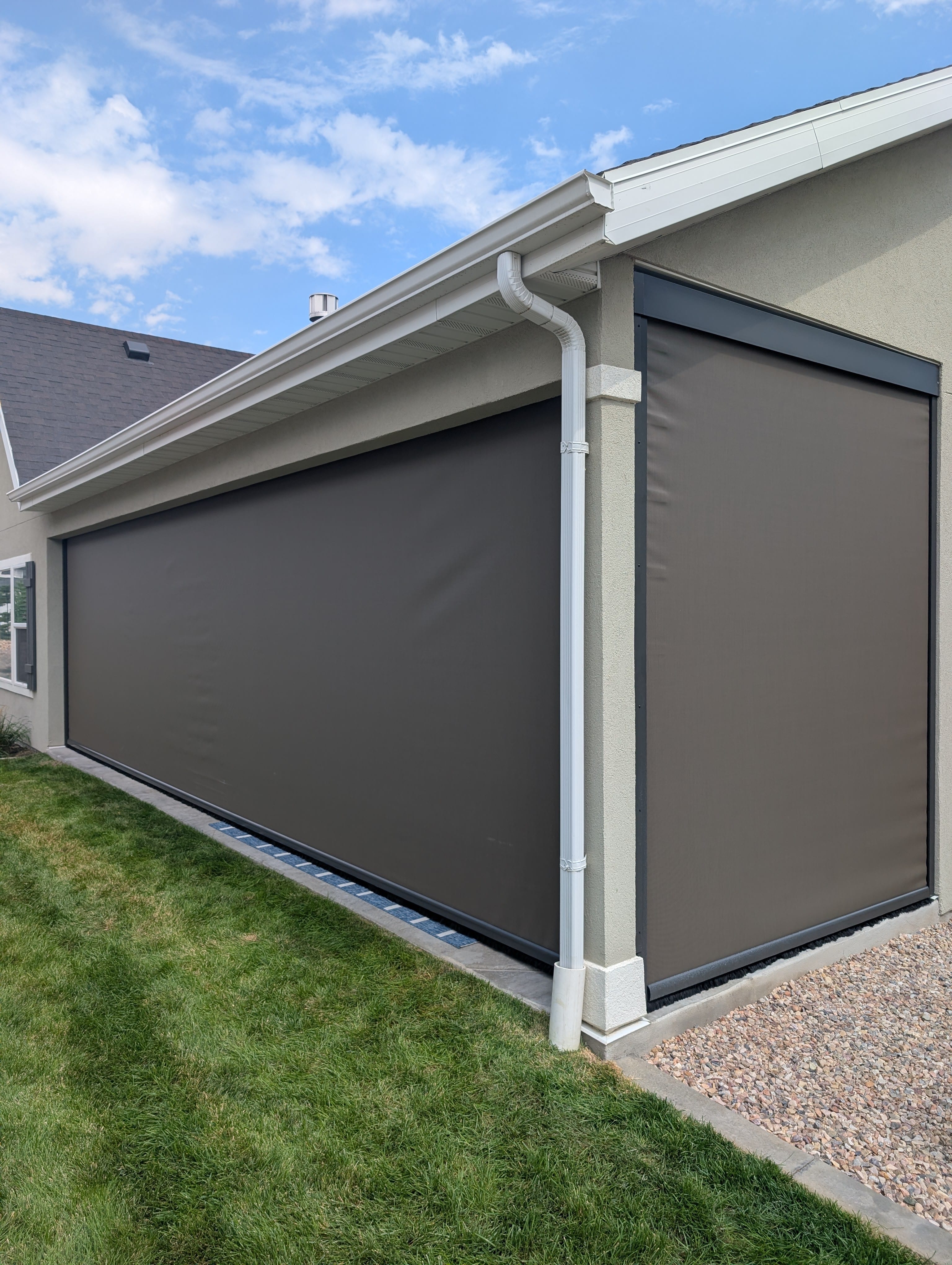 Two dark motorized patio screens installed on a Utah home