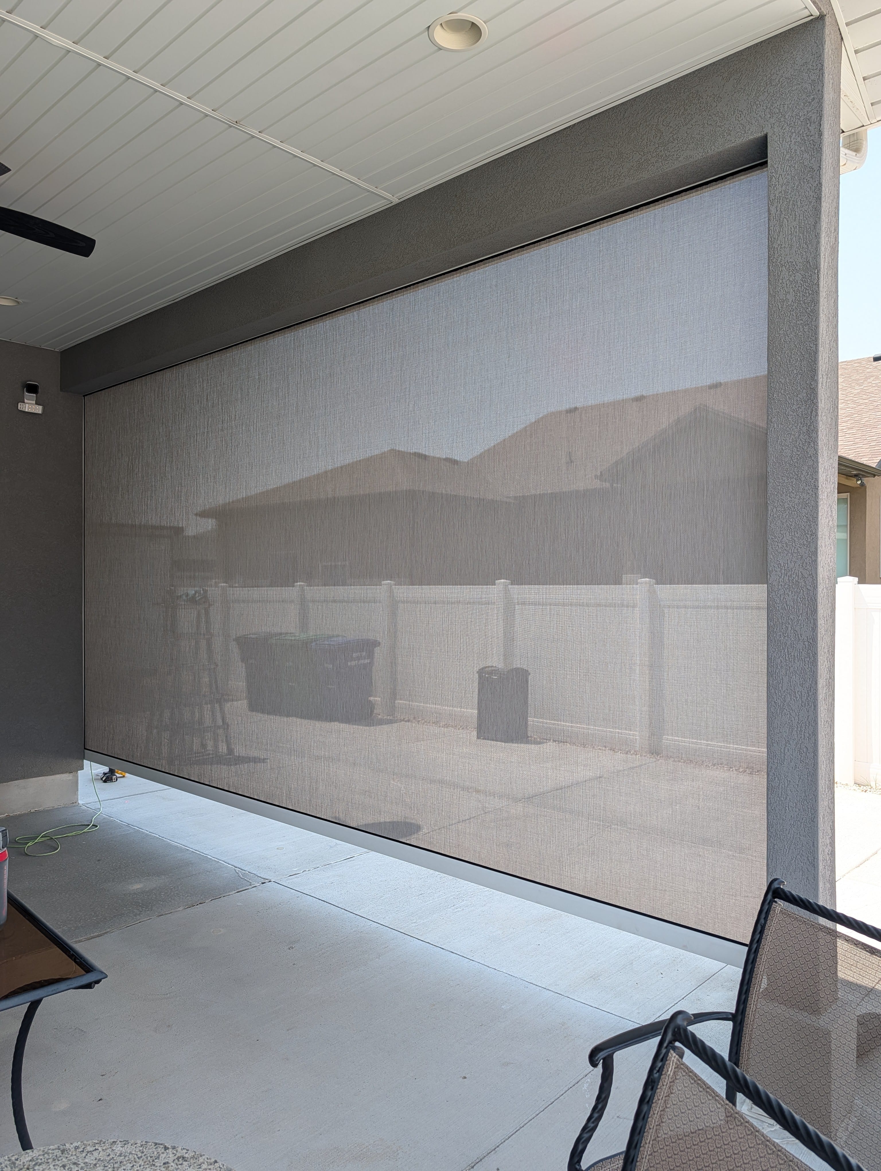 Motorized solar screen installed across a covered Utah patio opening