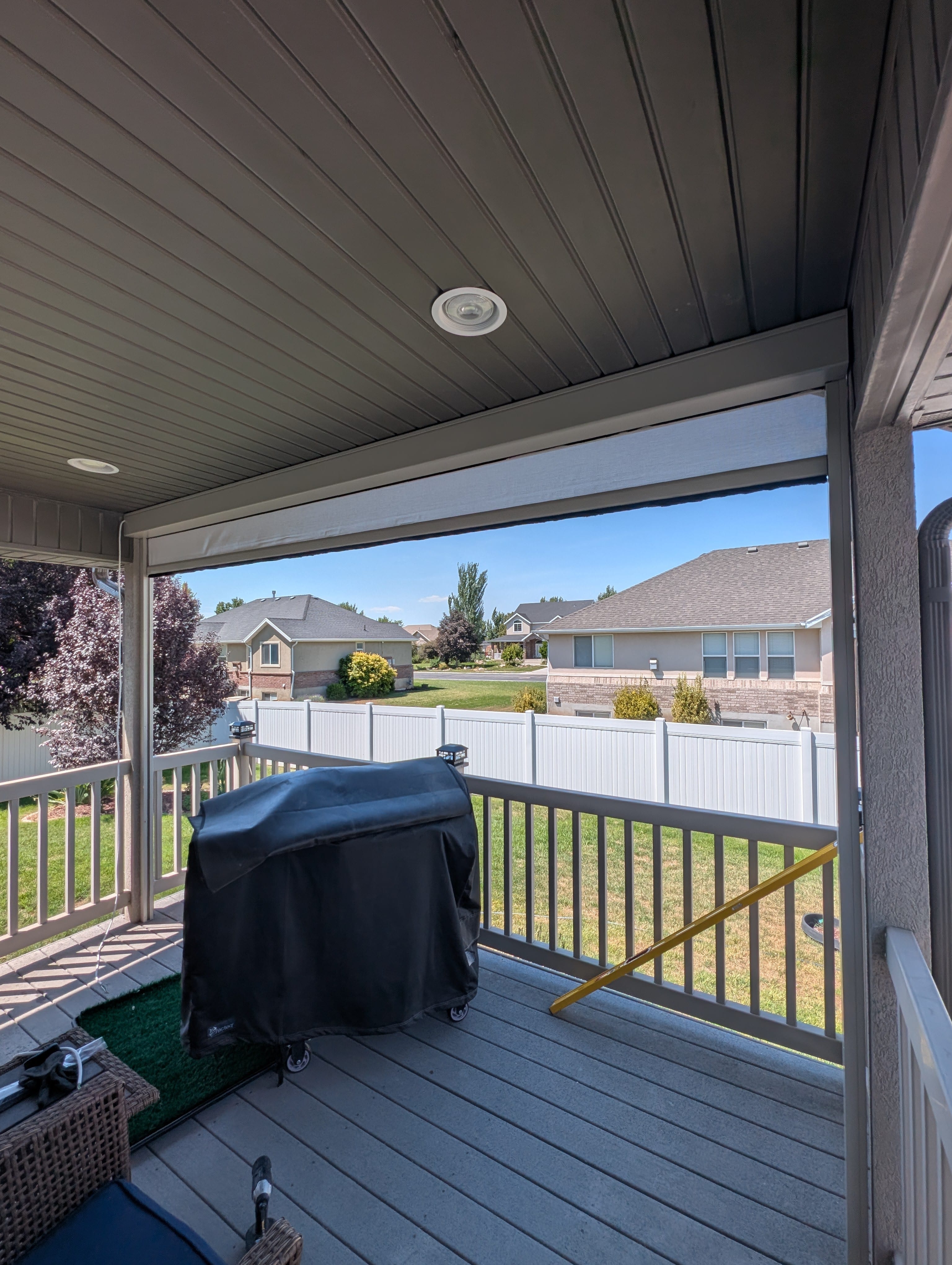 Partially lowered exterior solar shade installed under a covered Utah deck